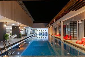 珍南海滩兰卡威别墅酒店的一座大型游泳池,位于一座配有红色椅子的建筑内