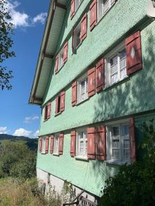 魏勒-锡默贝格Allgäu Cottage的绿色建筑的侧面设有红色窗户