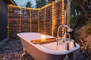 特鲁罗Luxury Glamping Cabin with Outdoor Bath on Cornish Flower Farm的浴缸配有蜡烛和一串灯光