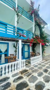 卡莫辛Pousada La Grécia的白色的建筑,有蓝色的窗户和鲜花