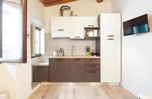普拉托CALIMARA18 25" from Florence AC SmartTV的厨房配有白色橱柜、水槽和冰箱。