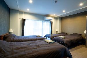 名古屋Usatsuno Osu的酒店客房设有三张床和窗户。