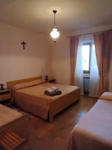 IelsiAgriturismo Masseria Testa Ciruglio的卧室配有两张床,墙上有一个十字架