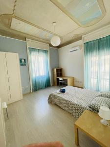 卡塔尼亚Deodato Guest House的一间卧室配有一张床、一张桌子和两个窗户