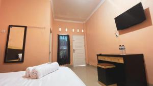 DukuPenginapan Malompek Syariah的一间卧室配有一张床、镜子和电视