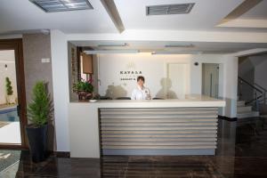 内亚卡瓦里Kavala Resort & Spa的站在大楼柜台后面的女人