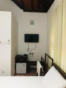 阿努拉德普勒Langama Thena - ළඟම තැන的卧室配有一张床,墙上配有电视。