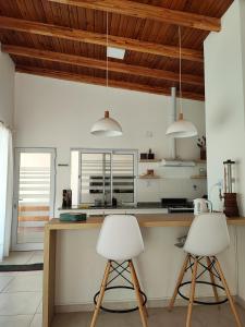 埃斯佩兰萨Quinta El Hornero的带木制天花板的厨房设有2张白色酒吧凳