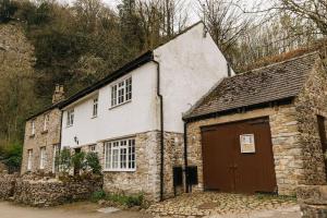 卡斯尔顿CLIFFE COTTAGE - Countryside Cottage in Castleton, Peak District National Park的一座古老的石头建筑,设有棕色的门