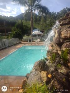 阿尤鲁奥卡Pousada nossa senhora的一座游泳池,其瀑布位于岩石墙旁