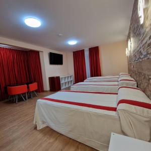托莱多Gavilanes 2 TOLEDO的酒店客房,配有两张带红色窗帘的床