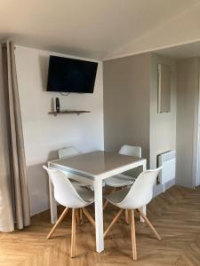 鲁西隆地区卡内Mobil home 3 chambres mar estang 4 étoiles !的餐桌、白色椅子和墙上的电视