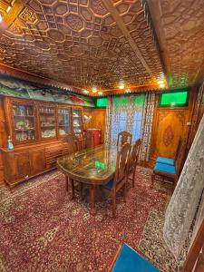 斯利那加Heritage Shreen Houseboat的一间带木桌和椅子的用餐室