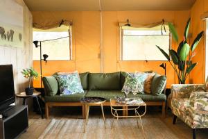 赫劳Glamping Safarilodge 'Grutte Fiif' met airco, extra keuken op veranda en privé achtertuin的客厅配有绿色沙发和桌子