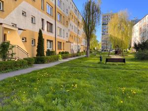 扎布热Apartament Ślęczka的公园,在建筑物旁边的草地上设有长凳