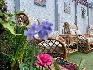 佩恩顿Seaside Homestay - Ensuite twin room with Kitchenette的一个带柳条椅和紫色花卉的庭院
