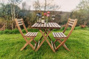特鲁罗Luxury Glamping Cabin with Outdoor Bath on Cornish Flower Farm的一张带两把椅子的野餐桌、瓶装葡萄酒和鲜花