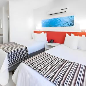 坎普斯戈伊塔卡济斯True América apart-hotel的白色和红色客房的两张床