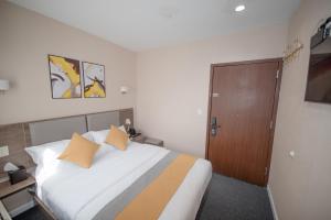 皇后区Flushing Garden Hotel的卧室配有一张带黄色枕头的大型白色床。
