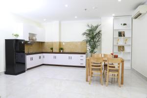胡志明市Thành Vinh Hotel的厨房配有白色橱柜和桌椅