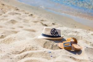 圣弗拉斯Onyx Beach Residence - Free Parking & Beach Access的沙滩上的帽子和凉鞋