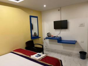 西里古里Hotel Shivanand的一间卧室配有一张床、一台电视和一把椅子