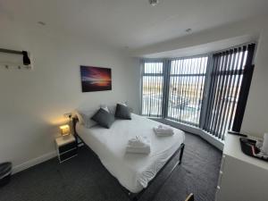 布莱克浦Blackpool Resort Hotel的一间卧室配有一张带白色床单和窗户的床。