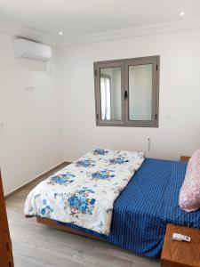 乌姆苏克Résidence Inès Djerba Appartement de Luxe的一间卧室配有一张带蓝色棉被的床和窗户。