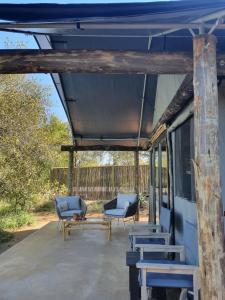 斯库库扎Umkumbe Bush Lodge - Luxury Tented Camp的带顶棚的门廊配有蓝色的椅子和桌子