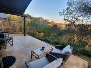 斯库库扎Umkumbe Bush Lodge - Luxury Tented Camp的天井配有2把椅子和1张镜子(桌子)
