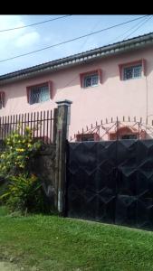 杜阿拉Vicky Appartements Palmengarten Douala Maképè Belavie的粉红色房子前面的围栏