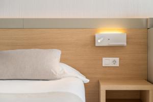 马盖鲁夫萨默斯酒店的卧室配有一张床,墙上有灯