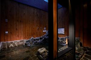 Yatomi Hotel Nuqu Natural Hot Spring的一间设有木墙的客房,里面装有岩石
