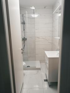 扎达尔Luce Gold Apartment的带淋浴和盥洗盆的白色浴室