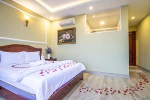 头顿Sea Memory Hotel的一间卧室配有白色床单和红色鲜花。