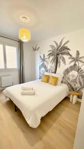 罗阿纳La Douceur Roannaise - Parking privé proche gare的卧室配有一张白色大床,墙上挂着棕榈树