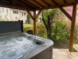 马尔赛Le Cottage d'Eleanor gîte de charme avec spa Jacuzzi privé的后院凉棚下的热水浴池