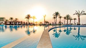 沙姆沙伊赫Sunrise Montemare Resort -Grand Select的棕榈树和日落的游泳池