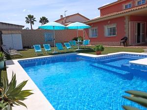 埃斯帕尔蒂纳斯El Capricho de Espartinas的房屋旁的游泳池配有椅子和遮阳伞