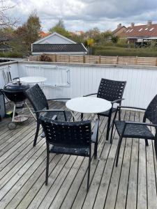 赫尔辛格Stor lys lejlighed med terrasse og altan的桌子、椅子和甲板上的烧烤架