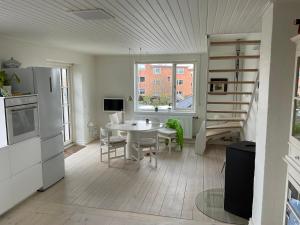 赫尔辛格Stor lys lejlighed med terrasse og altan的厨房以及带桌子和楼梯的客厅。