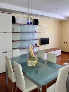 索托马里纳Chilli House的一间设有玻璃桌和白色椅子的用餐室