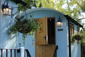 威尔斯浦Upper Gelli Luxury Holiday Lodge, Converted Dairy & Cosy Shepherds Huts的蓝色的小房子,有木门和灯