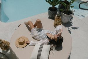 棕榈泉Yara Hotel - Adults Only的躺在游泳池旁桌子上的女人