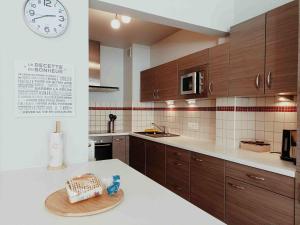 布鲁塞尔Cozy 2 bedroom apartment - metro Montgomery的厨房配有木制橱柜和墙上的时钟