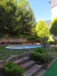 维耶拉Dúplex abuhardillado con vistas y parking的花园设有游泳池,种植了树木和鲜花