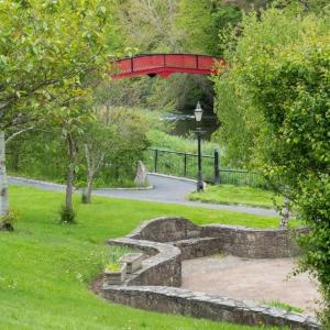 卡洛Riverside Lodge的一座红色的桥,横跨公园,有石头路