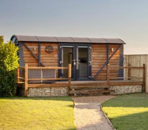 波士顿Yew Lodge - Shepherd's Hut Railway Carriage with "Hot Tub" - Sleeps 4 - Escape Completely!的小木屋设有门廊和木栅栏