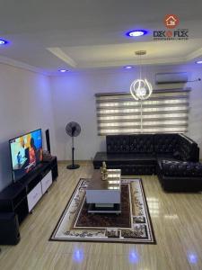 伊巴丹Dex & Flex Apartments的客厅配有黑色沙发和电视