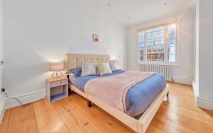 伦敦GARDEN Flat in Posh MEWS的一间卧室配有一张床和一张桌子上的台灯